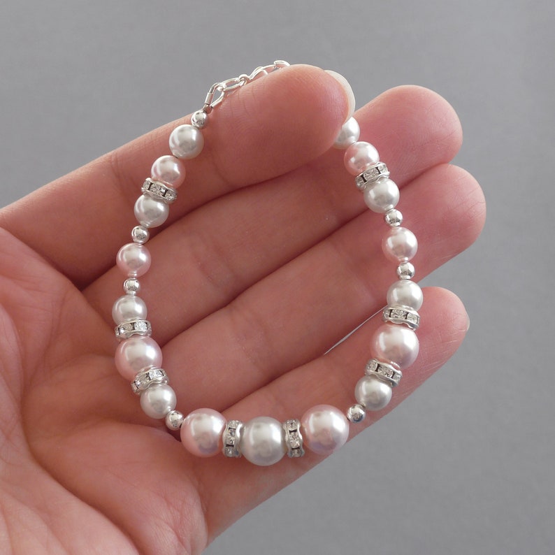 May include: A delicate bracelet featuring alternating pink and white pearls with silver accents and clear rhinestone embellishments.