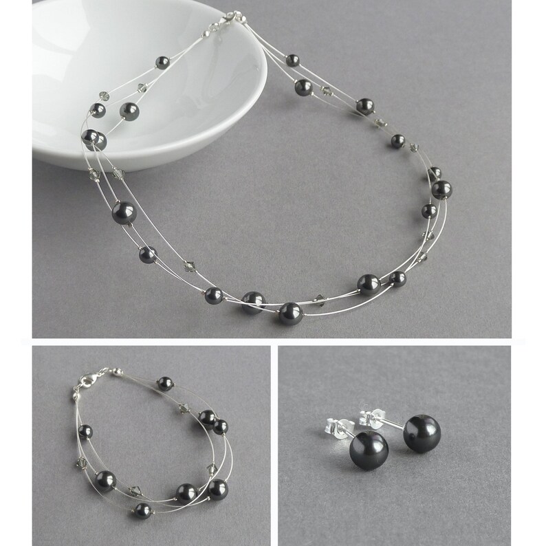 Puede incluir: Un conjunto de joyas de tres piezas que incluye un collar, una pulsera y unos pendientes. El conjunto est&aacute; hecho de metal plateado y presenta perlas negras.