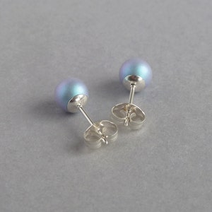 May include: A pair of iridescent blue stud earrings with silver posts and butterfly backs.