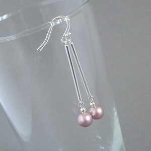 May include: Silver dangle earrings with a long, thin bar and a single pink pearl at the end of each earring.