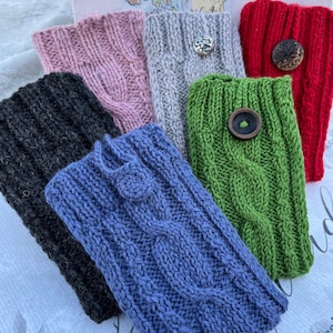 May include: Six knitted phone or tablet sleeves in various colors, including pink, gray, red, green, blue, and black. Each sleeve has a button and a decorative knot.