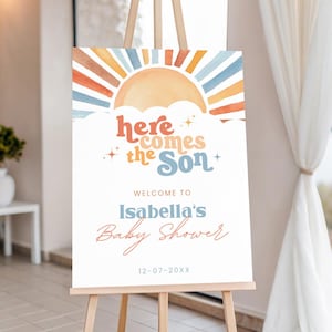 Pode incluir: Uma placa de boas-vindas para chá de bebê em um cavalete. A placa apresenta um desenho de sol em aquarela com raios laranja, azuis e amarelos. O texto inclui "Here Comes the Son", "Welcome to Isabella's Baby Shower" e uma data.