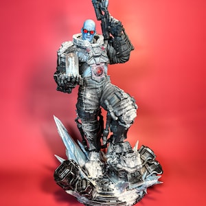 May include: A detailed action figure of Mr. Freeze from Batman, standing on a frozen base with a gun in his right hand and a vial of ice in his left hand. The figure is wearing a black and silver suit with a blue face and red goggles.