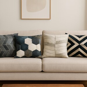 May include: A white sofa with four throw pillows. The pillows have geometric patterns in shades of gray, black, and white.