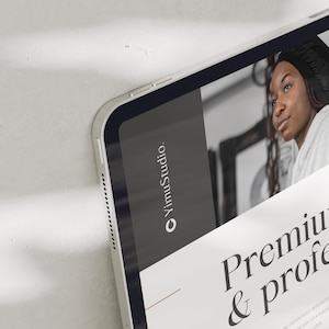 May include: A silver tablet with a dark gray screen displaying the text "YimuStudio." and a woman. The screen also shows the words "Premium & profe." The tablet is angled, revealing its side with a series of small holes.