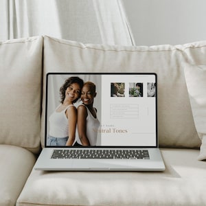 Może przedstawiać: Laptop wyświetlający prezentację zatytułowaną "Neutral Tones" z dwiema uśmiechniętymi kobietami w białych podkoszulkach. Laptop jest otwarty na beżowej kanapie.