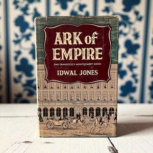 May include: A vintage book titled "Ark of Empire" with a maroon and white title on a green background. The cover features an illustration of a building and horse-drawn carriages. The author is Idwal Jones.