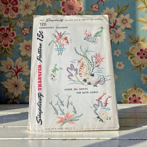 May include: A white ceramic mug with a black handle and the text "But First, Coffee" in a bold, black font. The mug is set against a blurred background, suggesting a cozy setting.