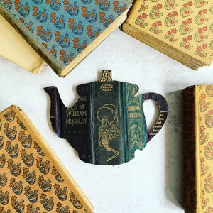 Pode incluir: Uma silhueta de bule de chá feita com as capas de livros antigos. Os livros têm títulos como "The Life of William McKinley", "My Country Home", "Brehms Tierleben" e "Golden Days in Southern Europe".