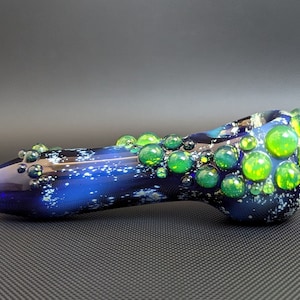 May include: A blue glass pipe with a galaxy-like design and green and yellow glass bubbles.