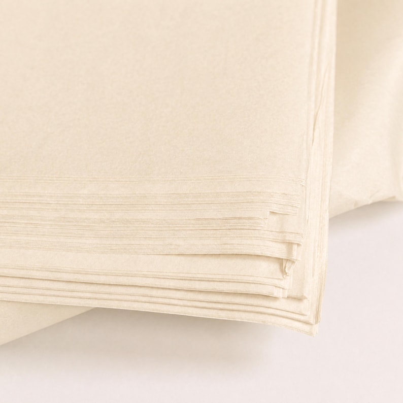 May include: A stack of folded, off-white paper napkins. The napkins are neatly arranged, with visible layers and a slightly textured surface. The color is a soft, creamy hue, suggesting a natural or eco-friendly material.