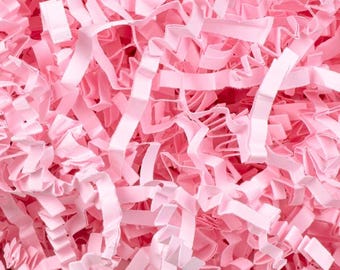 May include: Close-up of pink crinkle paper, a decorative packaging material. The paper is cut into thin strips and has a textured, ruffled appearance. The light pink color is consistent throughout the image, creating a soft, inviting aesthetic.