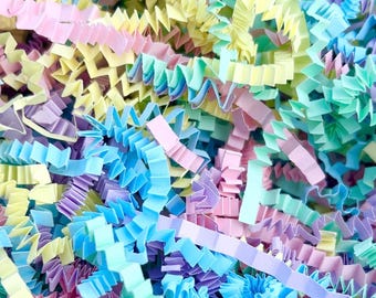 May include: Close-up of colorful crinkle paper in pastel shades of pink, blue, yellow, and green. The paper is shredded and has a textured, wavy appearance, ideal for gift packaging or decorative purposes.