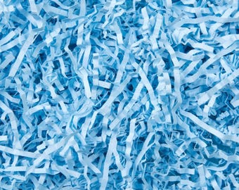 May include: A close-up shot of light blue shredded paper, filling the frame. The paper is cut into thin strips, creating a textured, layered effect. The color is a soft, pastel blue, ideal for packaging or decorative purposes.