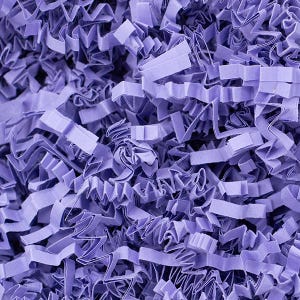 May include: A close-up shot of shredded lavender paper, suitable for gift packaging or crafts. The paper is cut into thin, wavy strips, creating a textured and voluminous appearance. The colour is a soft, muted purple, providing a delicate and elegant aesthetic.