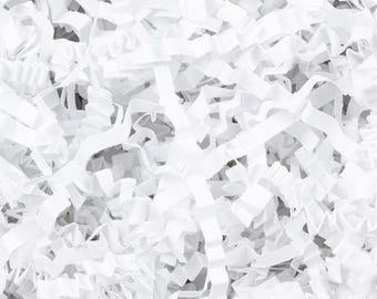 May include: Close-up of white crinkle paper, a decorative packaging material. The shredded paper is arranged in a dense, overlapping pattern, creating a textured, bright white surface. Ideal for gift boxes and baskets.