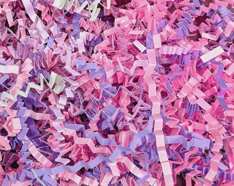 May include: Close-up of shredded paper in shades of pink, purple, and white. The paper is cut into long, thin strips, creating a textured and layered effect. The colors are vibrant and create a visually appealing background.