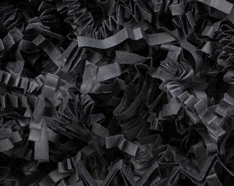 May include: Close-up of black crinkle cut paper, filling the frame. The paper is shredded into thin, wavy strips, creating a textured, layered effect. The dark color and irregular shapes suggest a packaging or craft material.