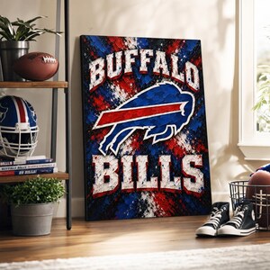 Pode incluir: Uma tela retangular com o logótipo dos Buffalo Bills em azul e vermelho, com o texto BUFFALO BILLS em letras brancas sobre um fundo texturado com salpicos de tinta vermelha, branca e azul.