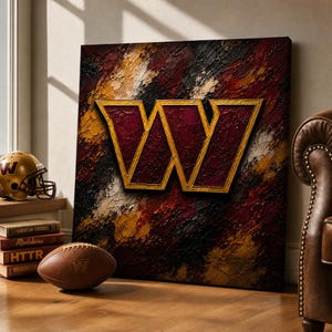 May include: A square canvas wall art piece featuring a large, gold-outlined letter W centered over a textured, impasto-style background of deep burgundy, black, and gold paint strokes. The artwork is displayed alongside a football and helmet.