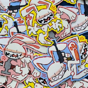 Può includere: Una collezione di adesivi di cartoni animati con un personaggio di coniglio bianco con un sorriso minaccioso, che tiene in mano una pistola. Gli adesivi hanno uno schema di colori giallo, rosa e blu con contorni neri. Il coniglio è in varie pose d'azione.