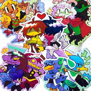 May include: A collection of die-cut vinyl stickers featuring colorful cartoon characters from the game Deltarune. The set includes Noelle, Ralsei, Kris, Susie, Berdly, and others in various poses, rendered in a vibrant, expressive art style with bold outlines.