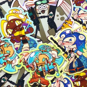 Puede incluir: Una colección de pegatinas de vinilo troqueladas que presentan coloridos personajes de dibujos animados con rasgos estilizados, incluyendo una figura de pelo azul con un arma, un personaje de pelo castaño con acentos amarillos y una figura central de pelo turquesa.