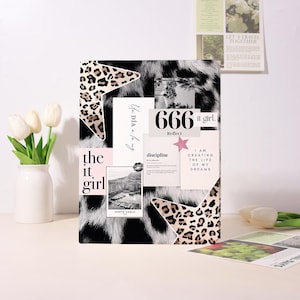 Può includere: Un collage decorativo con uno sfondo a stampa animalier in bianco e nero. Il collage include forme di stelle con stampa leopardata, una foto di Monte Carlo e il testo che dice "the it girl", "666 it girl" e "I am creating the life of my dreams."