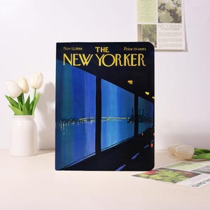 May include: A copy of The New Yorker magazine from Nov. 12, 1966, featuring a nighttime cityscape illustration with a bridge and city lights. The magazine cover is predominantly dark blue and black with yellow text.