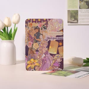 May include: A rectangular purple case with a collage of fairytale illustrations. The design includes a princess, a prince, flowers, and the text "She's pure magic".