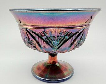 May include: An iridescent carnival glass bowl with a pedestal base, featuring a deep purple and blue metallic sheen. The exterior surface is decorated with pressed geometric patterns, including starburst motifs and fine stippled textures.