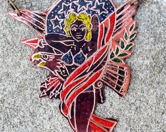 Op de afbeelding: Een koperen ketting met een hanger met een vrouw die een Amerikaanse vlag vasthoudt met een Amerikaanse zeearend. De hanger is geschilderd met rode, witte, blauwe en gouden accenten.