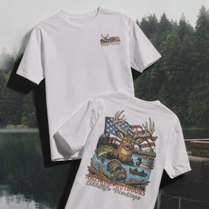 以下が含まれることがあります： 2つの白いTシャツ。1つのシャツには、胸に鹿とアメリカ国旗の小さなグラフィックがあります。もう1つのシャツの背面には、鹿、アメリカ国旗、魚、七面鳥、および「AMERICAN OUTDOORS Wildlife Heritage」というテキストが描かれた大きなグラフィックがあります。