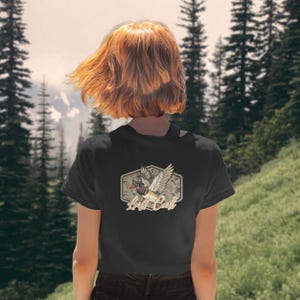 May include: Black t-shirt featuring a duck graphic with the text "Lost Call" in a vintage style. The design includes a duck in flight with outstretched wings, set against a camouflage pattern. The shirt is a classic crew neck.