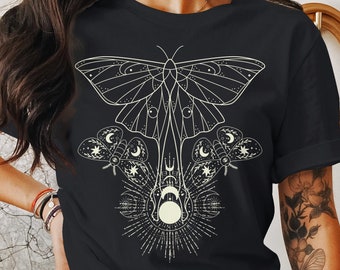 May include: Black t-shirt with a white graphic of a moth with wings spread, surrounded by smaller moths and a crescent moon.