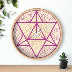 May include: A round wooden clock with a pink and white geometric design. The clock face features a pink star with a white outline and a white clock hand.