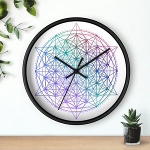 May include: A black framed clock with a white face and a geometric design in shades of purple, blue, and green. The clock hands are black.