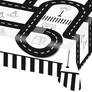 Peut inclure: Nappe en plastique noire et blanche avec un motif de route. La nappe présente une station-service, des cônes de signalisation, un panneau d'arrêt et une voie cyclable. La nappe a une bordure rayée noire et blanche.