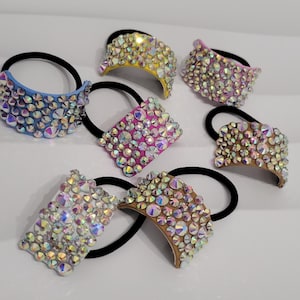 Peut inclure: Plusieurs élastiques à cheveux ornés de strass irisés. Les élastiques sont disponibles en différentes couleurs, notamment bleu, jaune, rose et marron. Chaque élastique a un élastique noir.