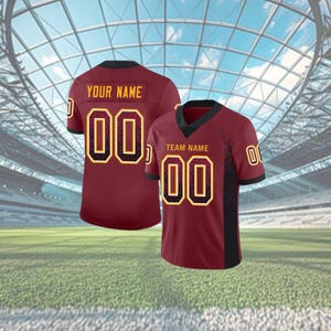Puede incluir: Camiseta de f&uacute;tbol granate con detalles en negro y dorado. La camiseta muestra el n&uacute;mero "00" en dorado con un contorno negro. La parte trasera de la camiseta tiene "YOUR NAME" impreso encima del n&uacute;mero. La parte delantera tiene "TEAM NAME".