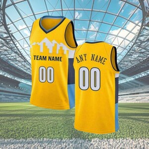 May include: Two yellow basketball vests with blue and white detailing. One vest reads "TEAM NAME" and "00", the other reads "ANY NAME" and "00". The vests feature a cityscape design.