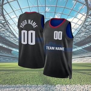 May include: Two black basketball jerseys with white numbers and text. One jersey reads "YOUR NAME" above the number "00" on the back. The other jersey reads "TEAM NAME" below the number "00" on the front. Both jerseys have a blue and red trim.