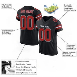 Puede incluir: Camiseta de f&uacute;tbol negra con detalles rojos y blancos. Presenta cuello en V, mangas cortas y el n&uacute;mero "00" en rojo con contorno blanco. La camiseta tiene texto que dice "ANY NAME" y "TEAM NAME". La tela es transpirable, de secado r&aacute;pido y absorbe la humedad.