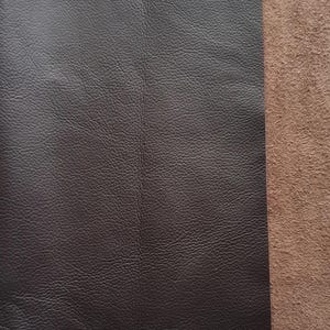 May include: Close-up of two pieces of leather, one dark brown and smooth, the other a lighter brown and suede-like.