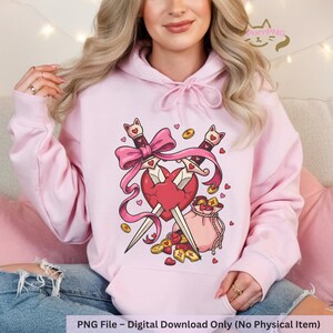 May include: Light pink hoodie with a graphic design featuring two crossed swords piercing a broken heart, a pink bow, coins, and a small bag. The design is in a cartoon style. The text at the bottom reads "PNG File - Digital Download Only (No Physical Item)".