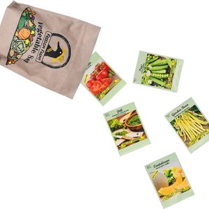 Op de afbeelding: Een bruine papieren zak met het label Freedom Farms Vegetable Set en een zwart vogel-logo, vergezeld van vijf individuele zaadzakjes met afbeeldingen van tomaten, erwten, dille, sperziebonen en meloen, allemaal voorzien van de naam Valley Greene.