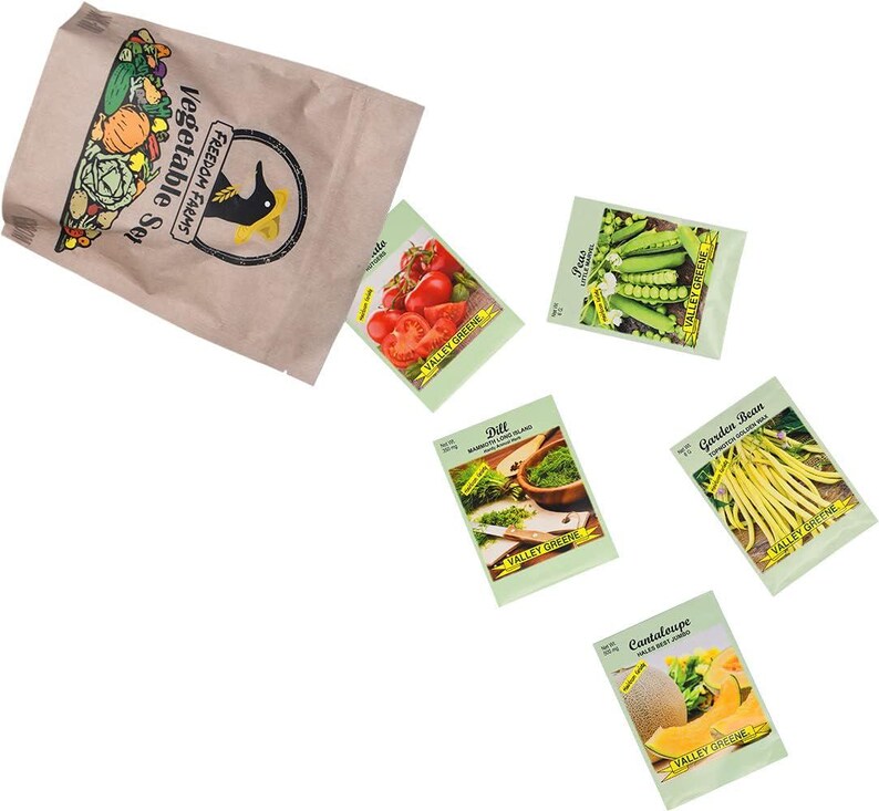 Op de afbeelding: Een bruine papieren zak met het label Freedom Farms Vegetable Set en een zwart vogel-logo, vergezeld van vijf individuele zaadzakjes met afbeeldingen van tomaten, erwten, dille, sperziebonen en meloen, allemaal voorzien van de naam Valley Greene.