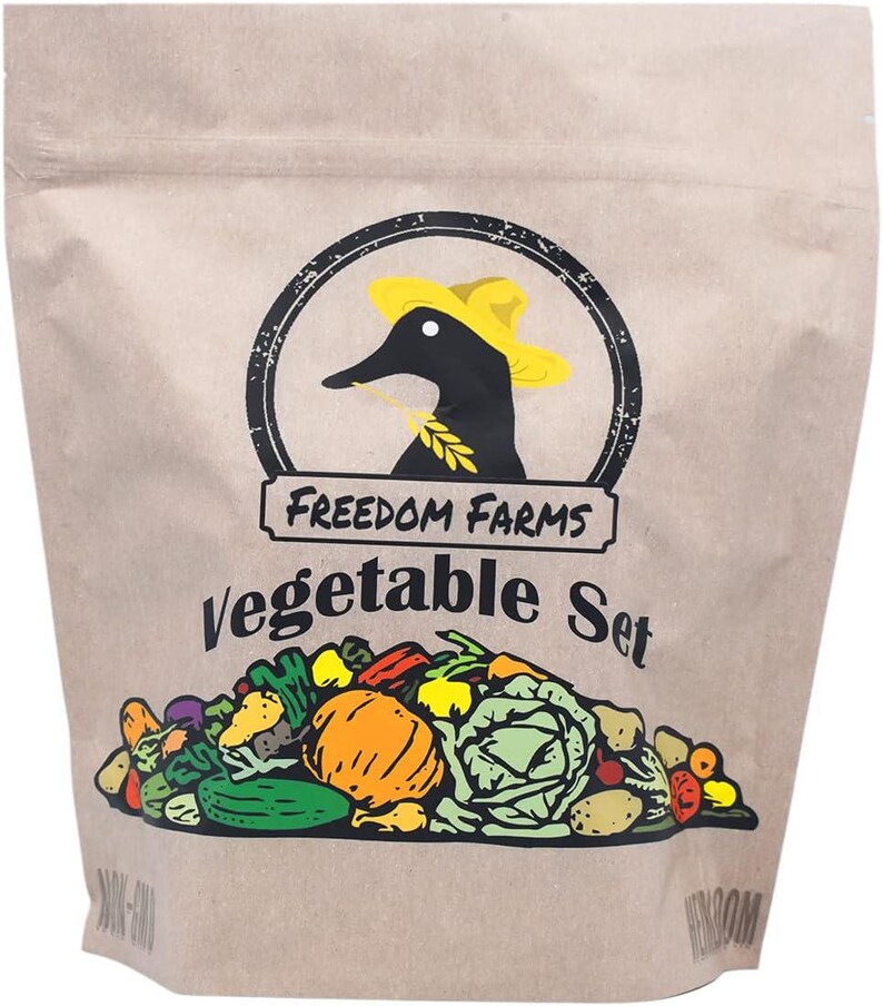 Op de afbeelding: Een beige papieren zakje met het label Freedom Farms Vegetable Set. Het logo toont een zwarte eend met een gele hoed die een graanstengel vasthoudt. Onder de tekst staat een kleurrijke grafische illustratie van diverse groenten zoals pompoen.