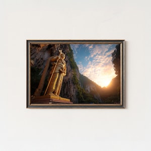 May include: Framed print featuring a golden statue of a figure holding a staff, set against a backdrop of a mountain and a sunset. The artwork is displayed in a dark brown frame, adding a touch of elegance to the scene.