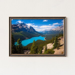 Peut inclure: Impression encadrée d'un paysage avec un lac turquoise entre des montagnes enneigées sous un ciel bleu nuageux. Des forêts vertes entourent le lac. Le cadre est sombre avec des accents dorés, capturant la beauté naturelle.